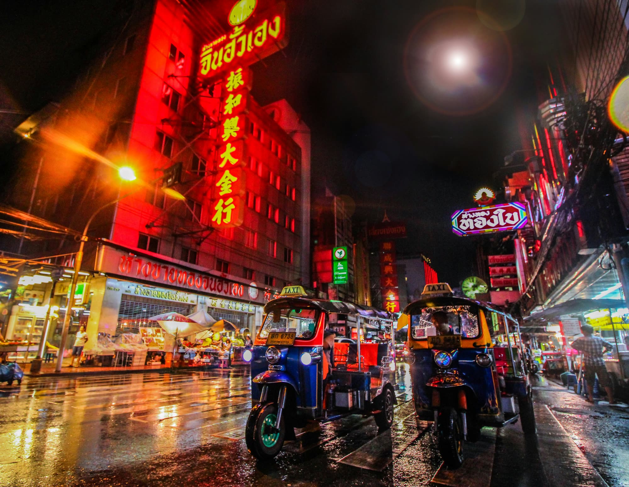 Neon signs and tuk-tuks on a rainy night in Yaowarat, Bangkok's Chinatown