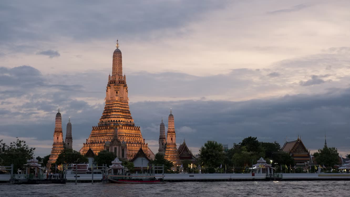 Wat Arun lit up at dusk across the Chao Phraya river in Bangkok
